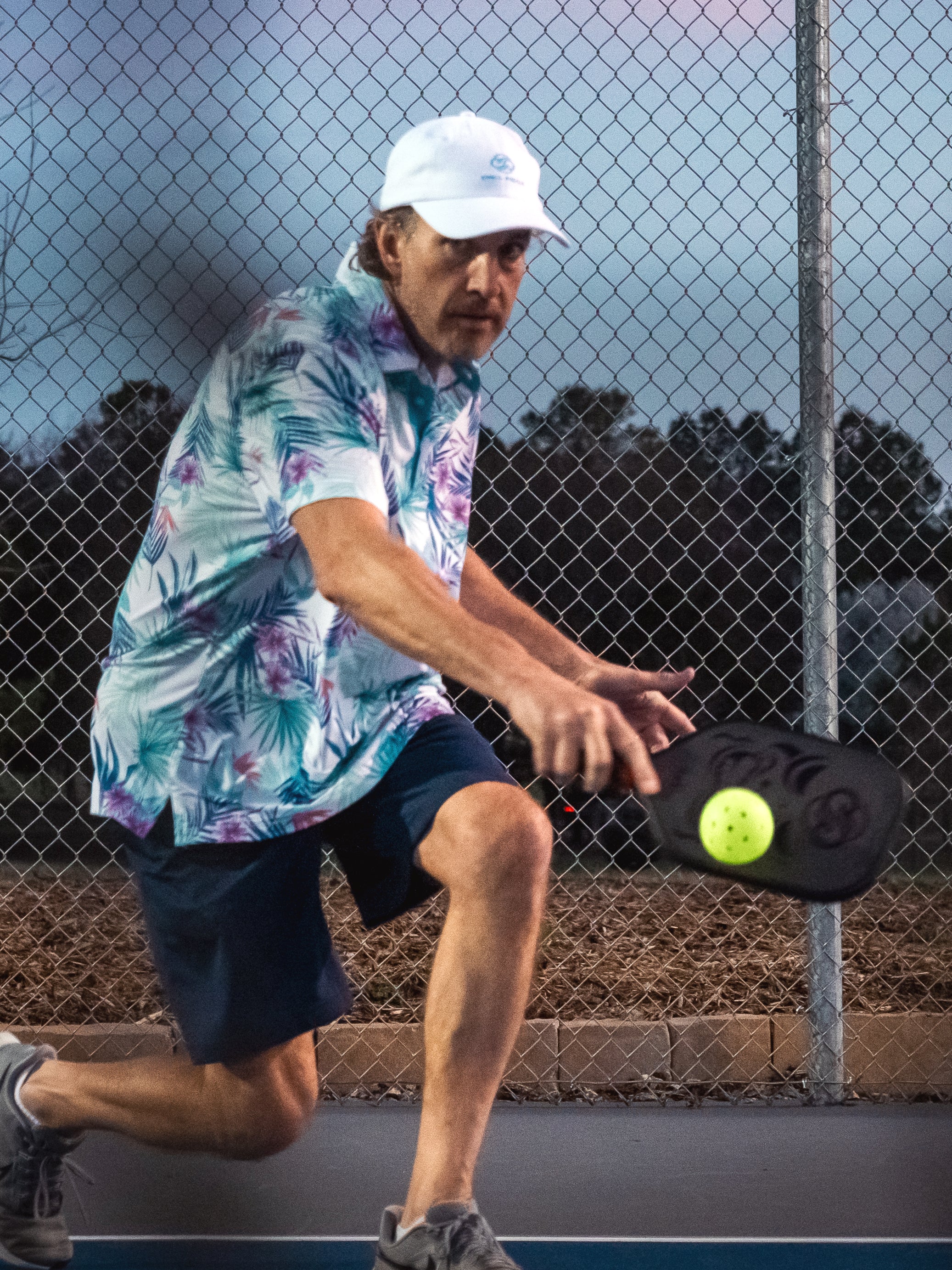 Chill Pickle athlete executing a low backhand shot with a Kahuna performance paddle on outdoor court