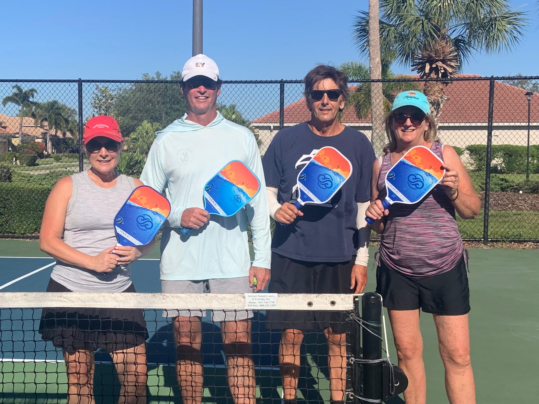Group of pickleball players holding Chill Pickle Makai paddles outdoors on a sunny court
