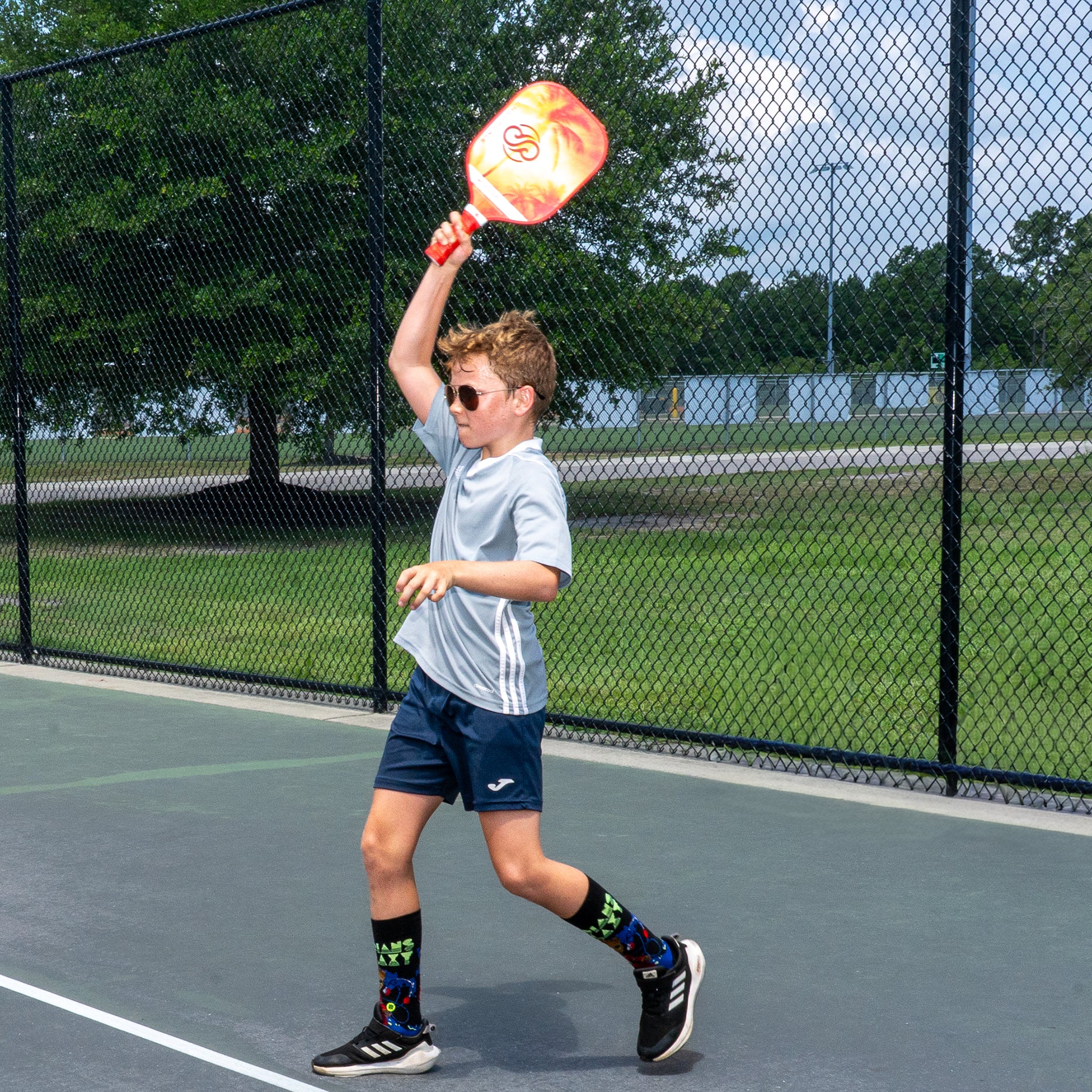 Young beginner learning to hit a pickleball on an outdoor practice court