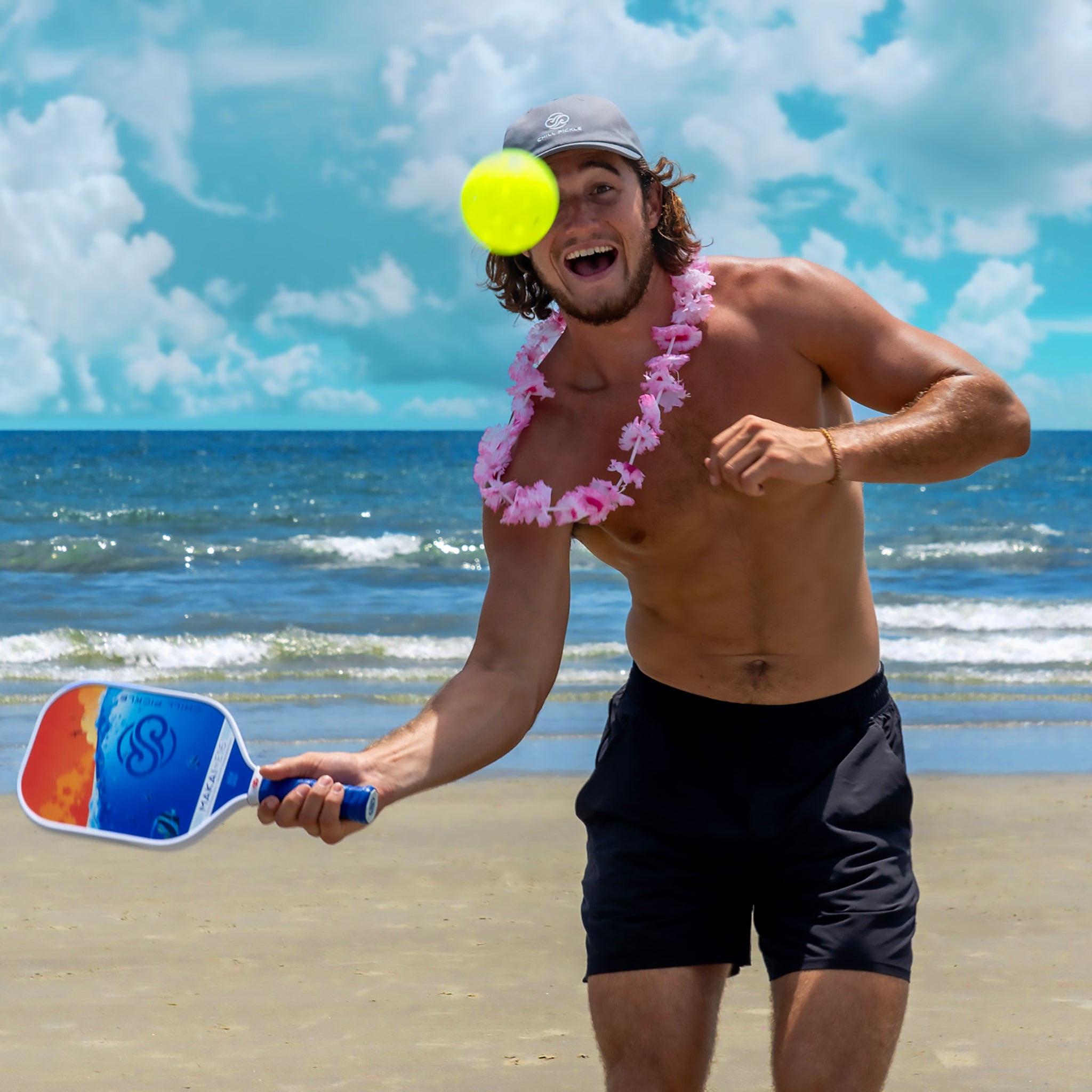 Pickleball player striking an overhead shot on a sandy beach court with ocean backdrop